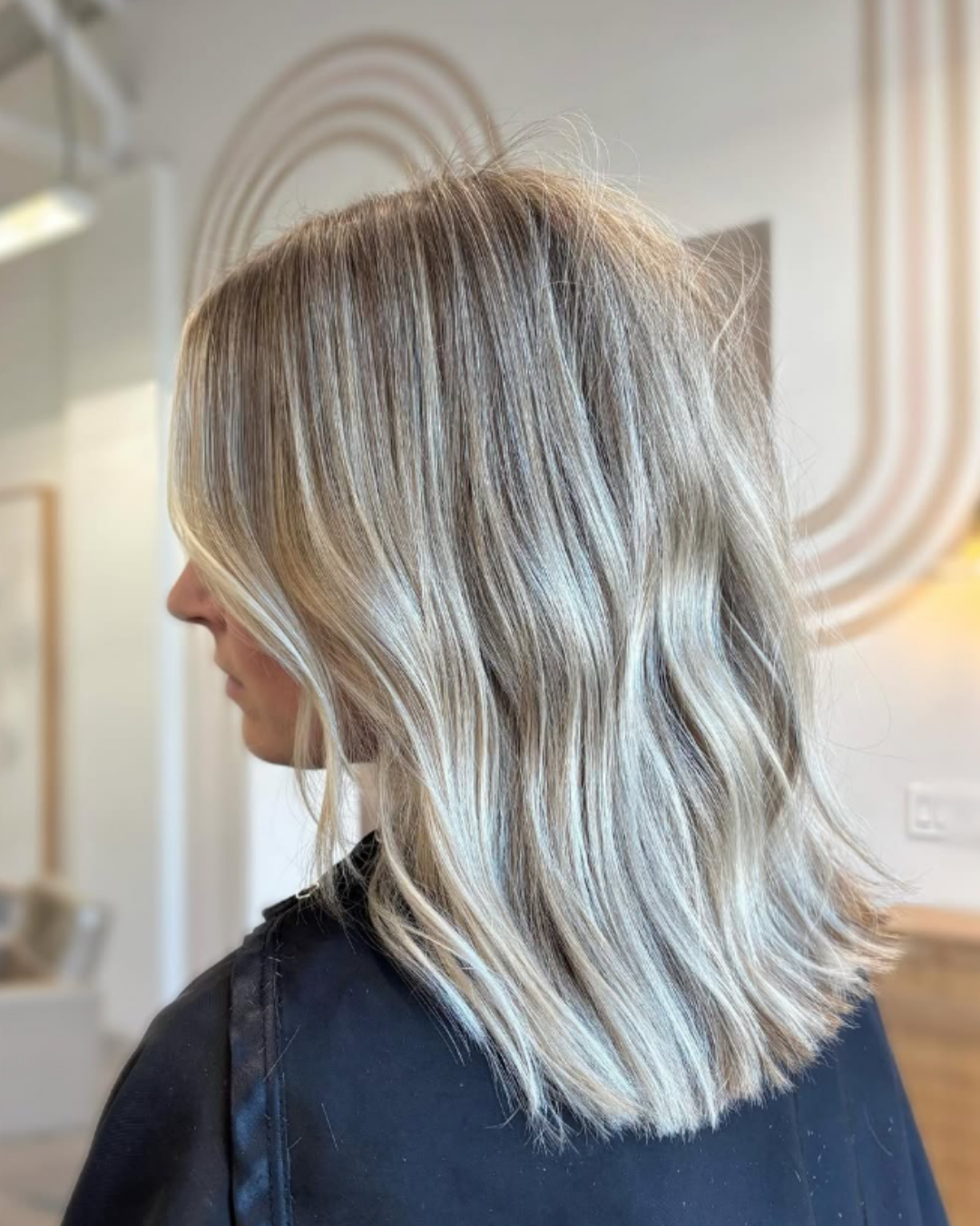 Side view of a blunt, wavy bob with cool-toned beige blonde highlights by Jules.