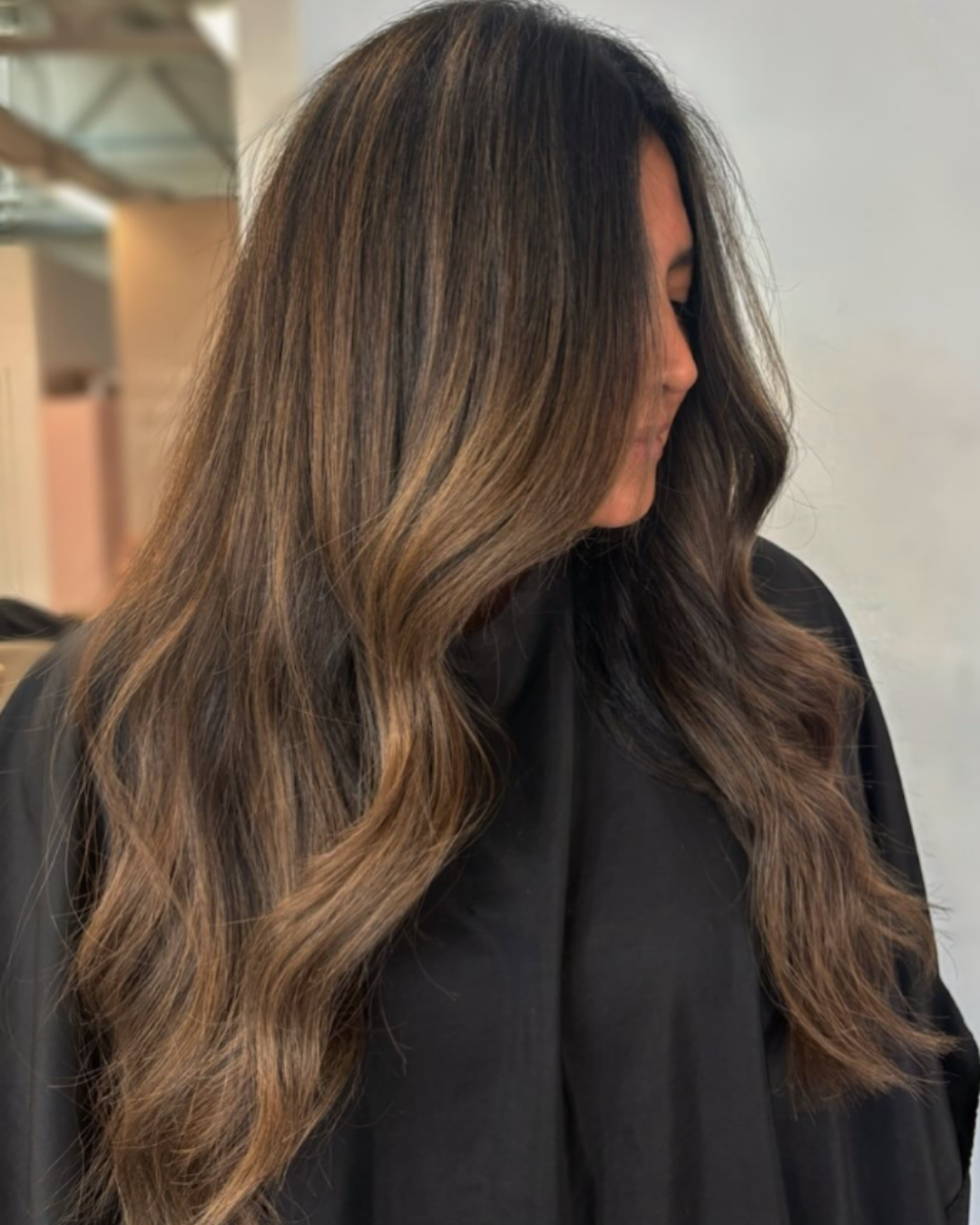 Long brunette hair with subtle caramel balayage highlights for added depth and dimension by Amelia.