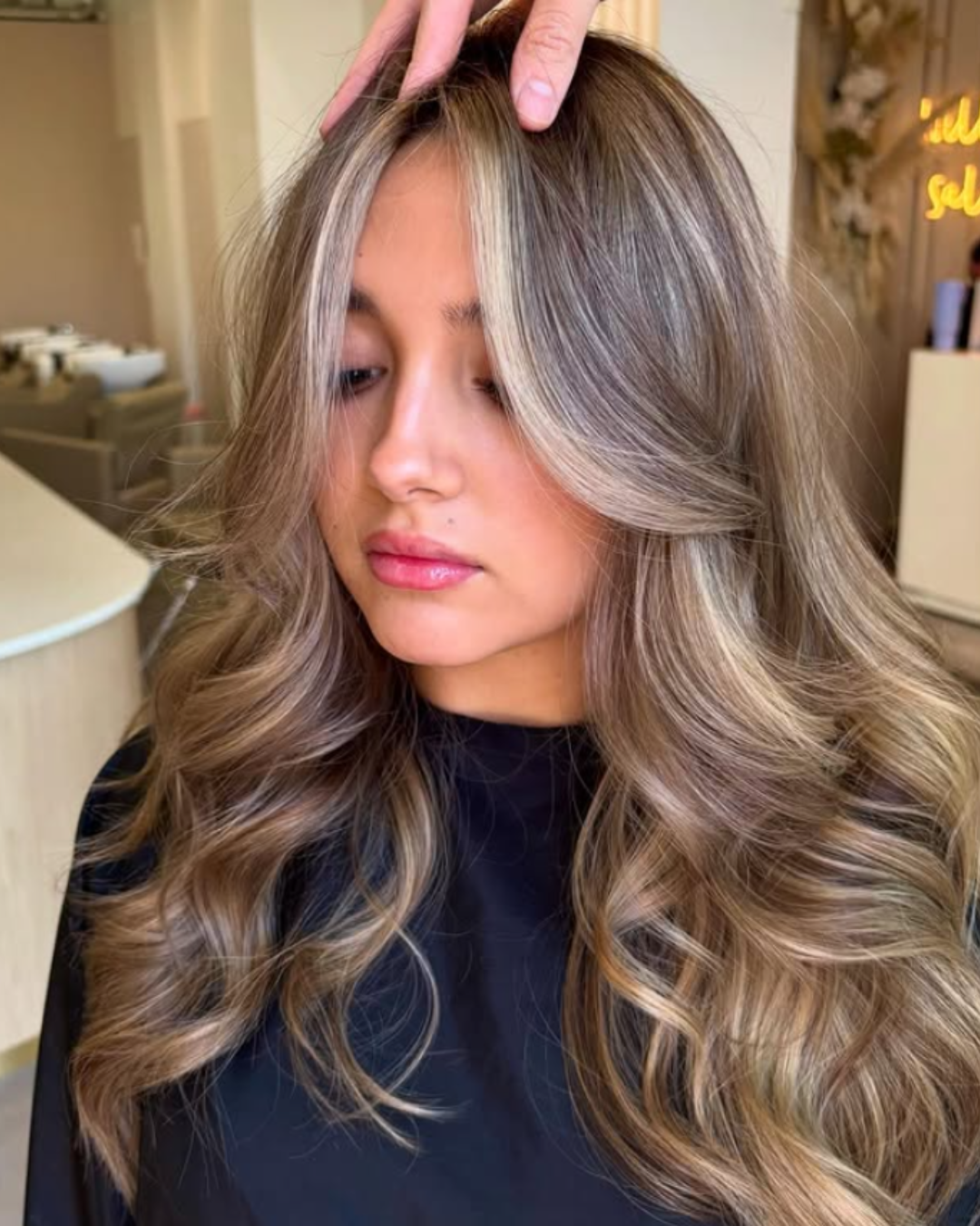 Client with long, voluminous brunette hair featuring bright blonde face-framing highlights by Jasmine.