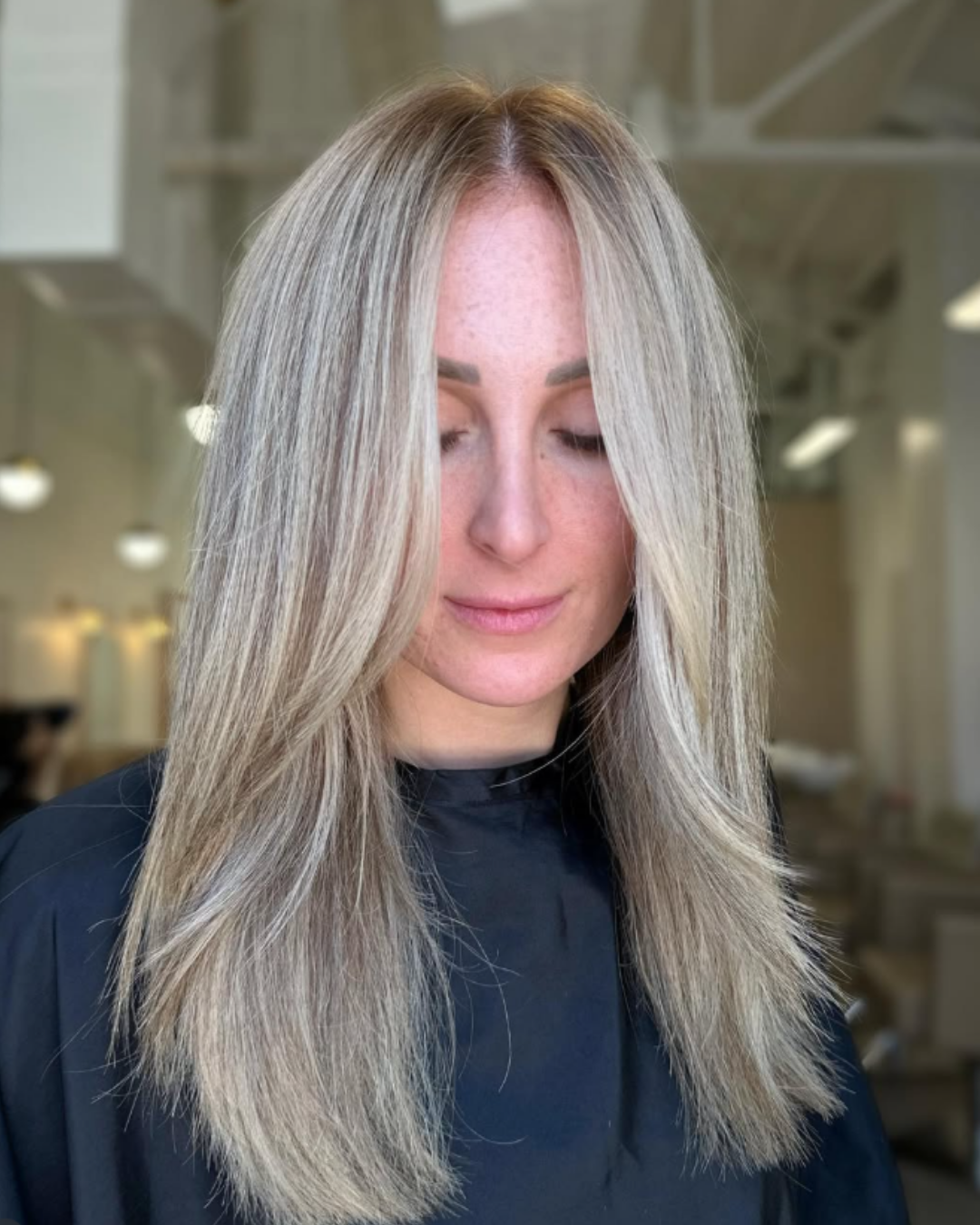 Straight blonde hair with a mix of cool-toned highlights and dimensional lowlights by Brianna.