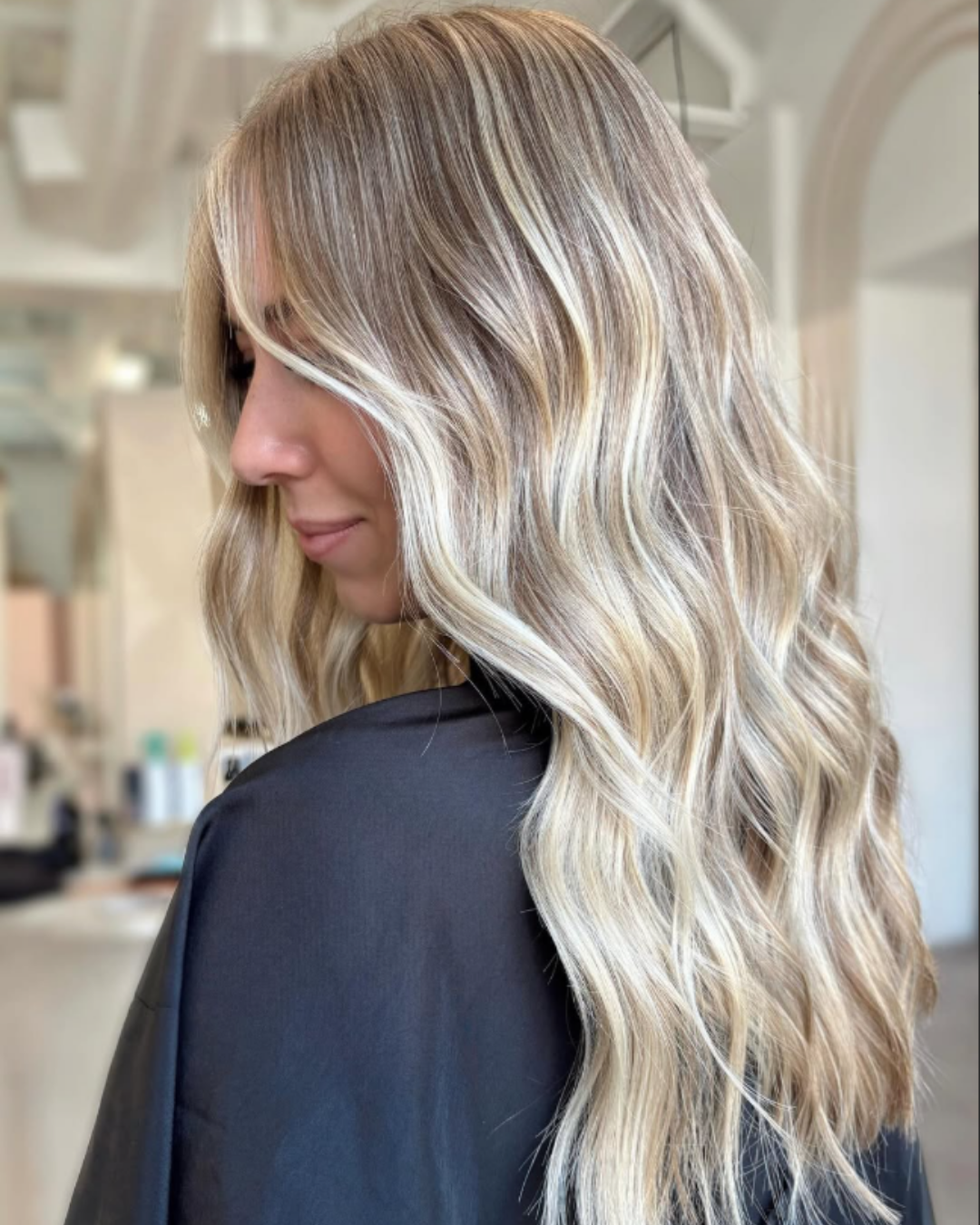 Lived-in blonde hair, featuring bright face-framing highlights and soft waves by Jules.