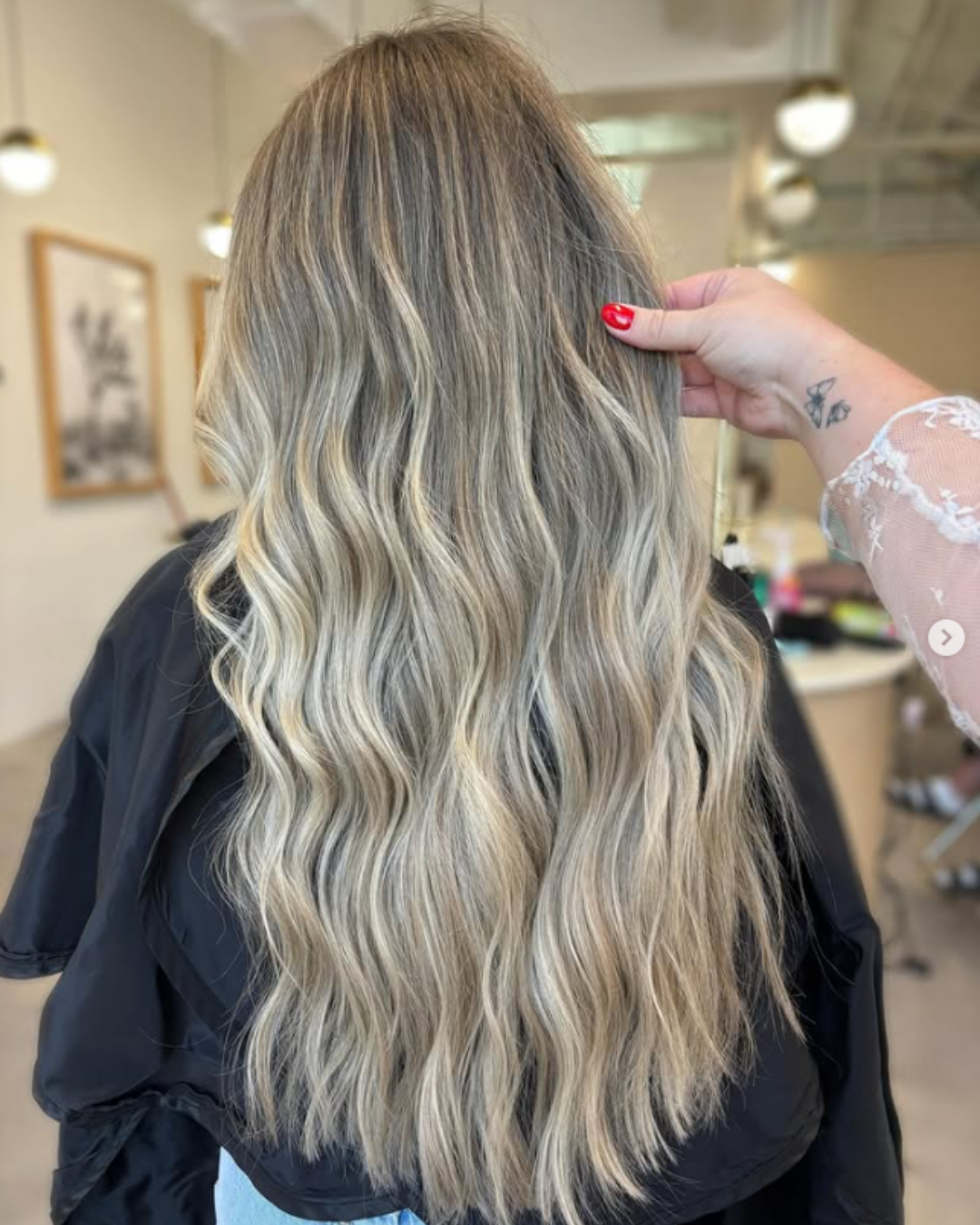 Back view of long, wavy hair featuring soft dimensional blonde highlights and beige tones by Jules.