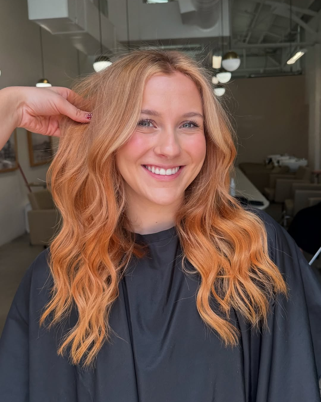 Smiling woman with long, wavy strawberry blonde hair and warm copper tones by Ryan.