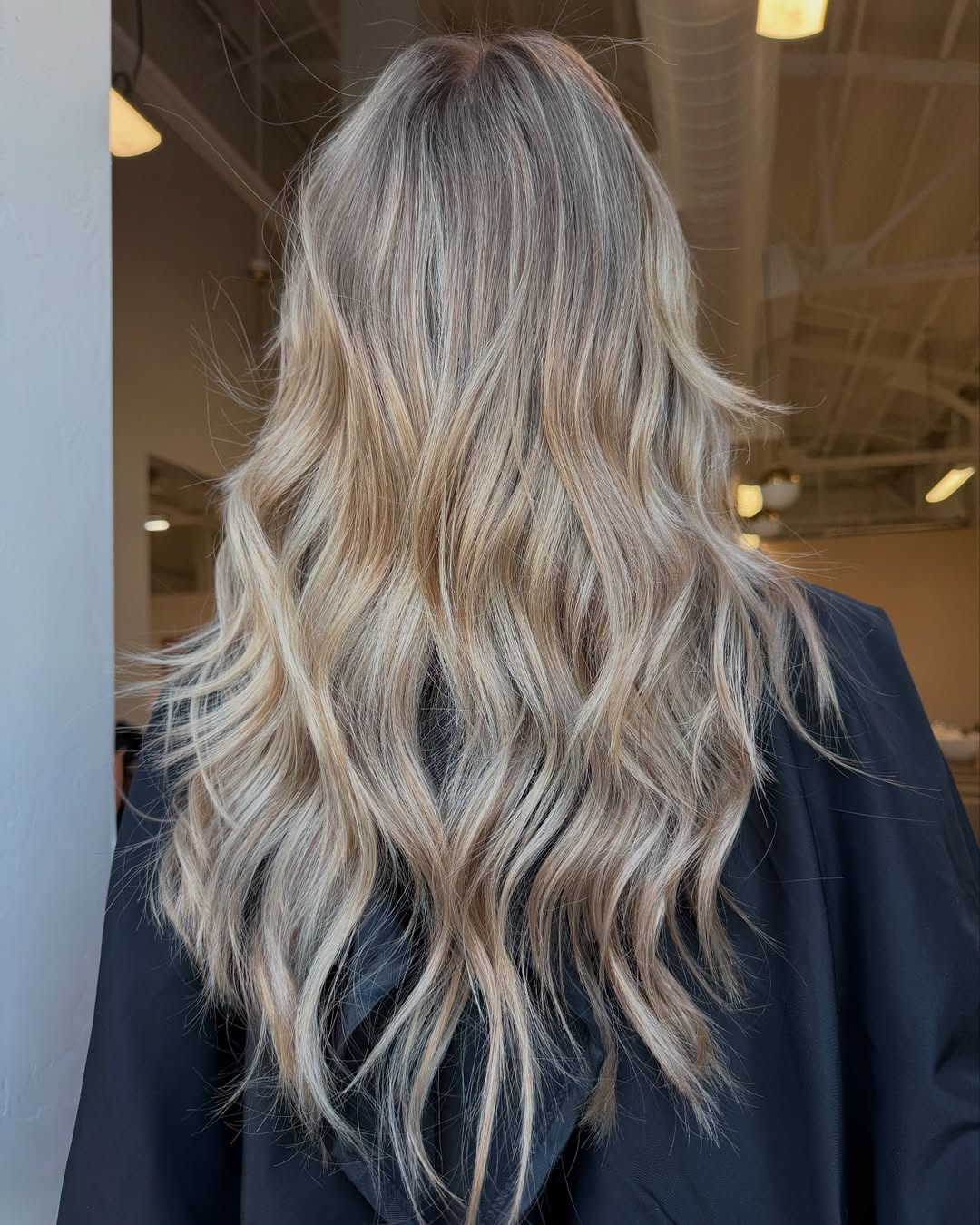 Back view of long, beachy waved blonde hair featuring dimensional blonde highlights and lowlights by Britttany