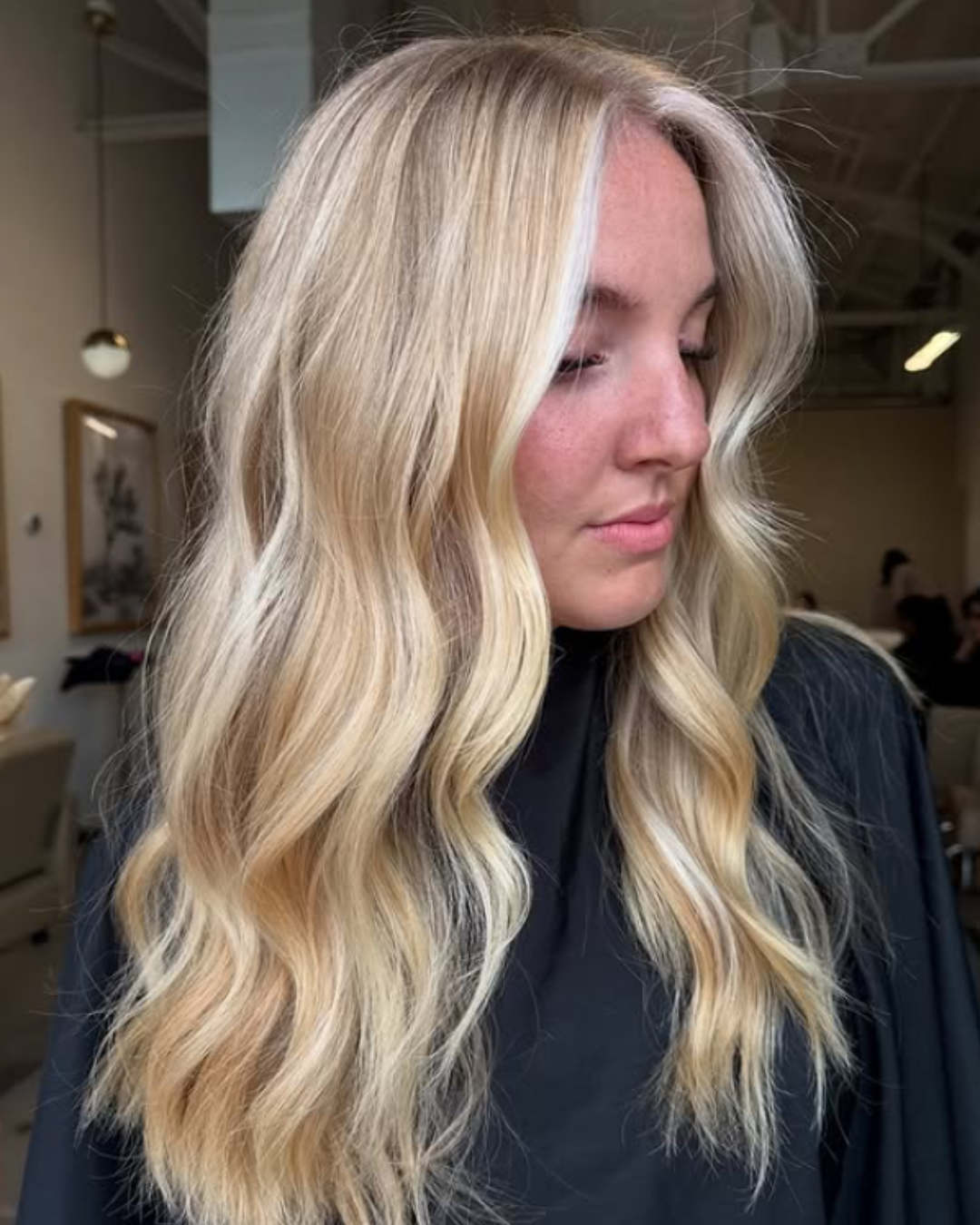 Woman with bright golden blonde hair styled in soft waves with light money piece highlights by Britttany