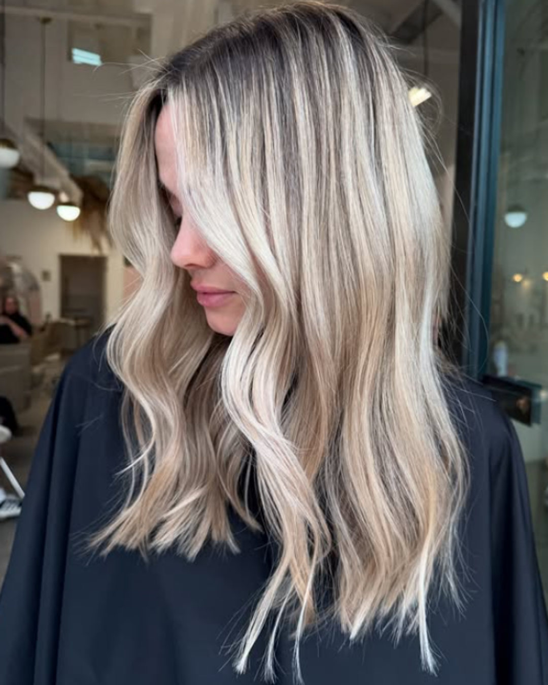 Woman with bright summer blonde hair featuring cool platinum highlights and soft wavy layers by Britttany
