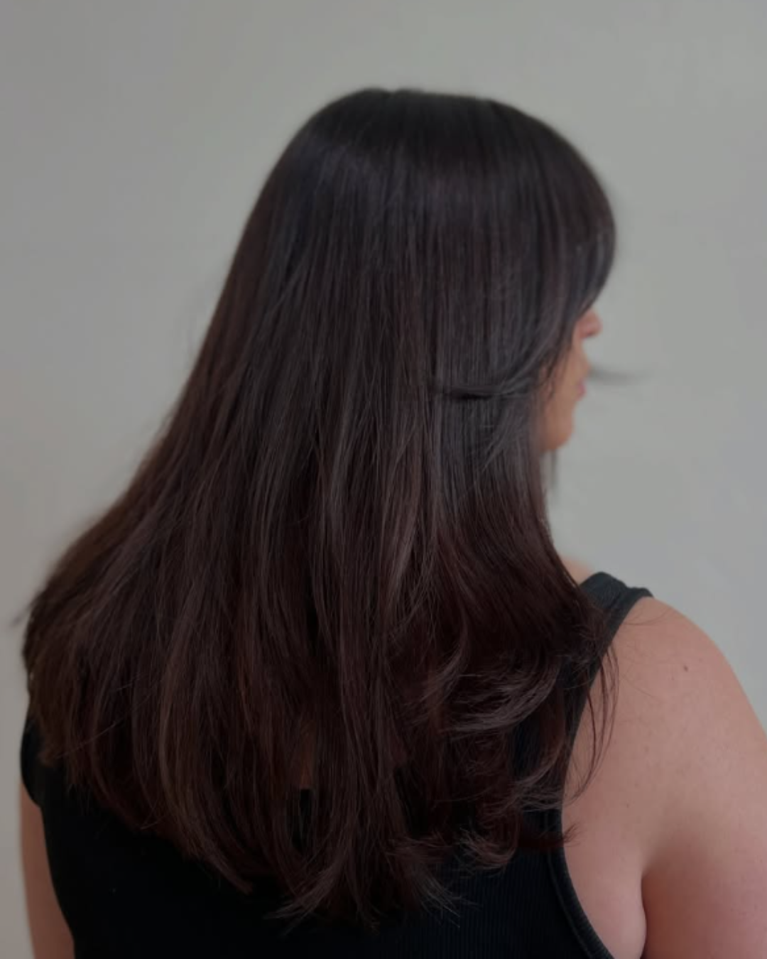 Back view of long dark espresso brown hair with smooth layers and blowout ends by Desirae.