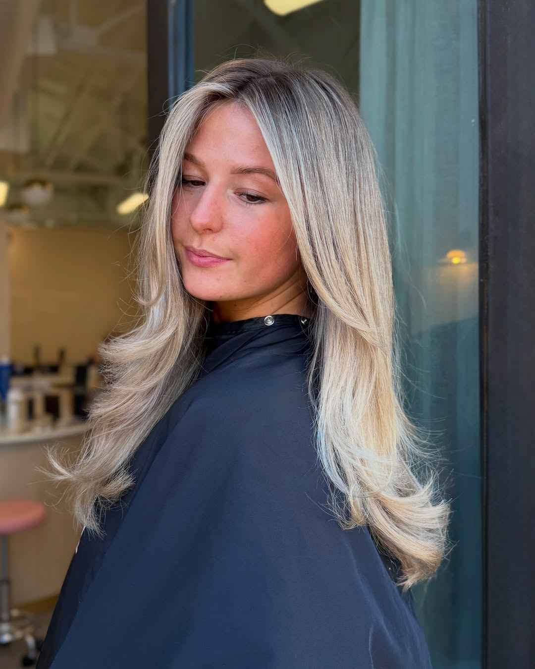 Woman with bright blonde face-framing highlights and subtle dimensional blonde layers by Brittany